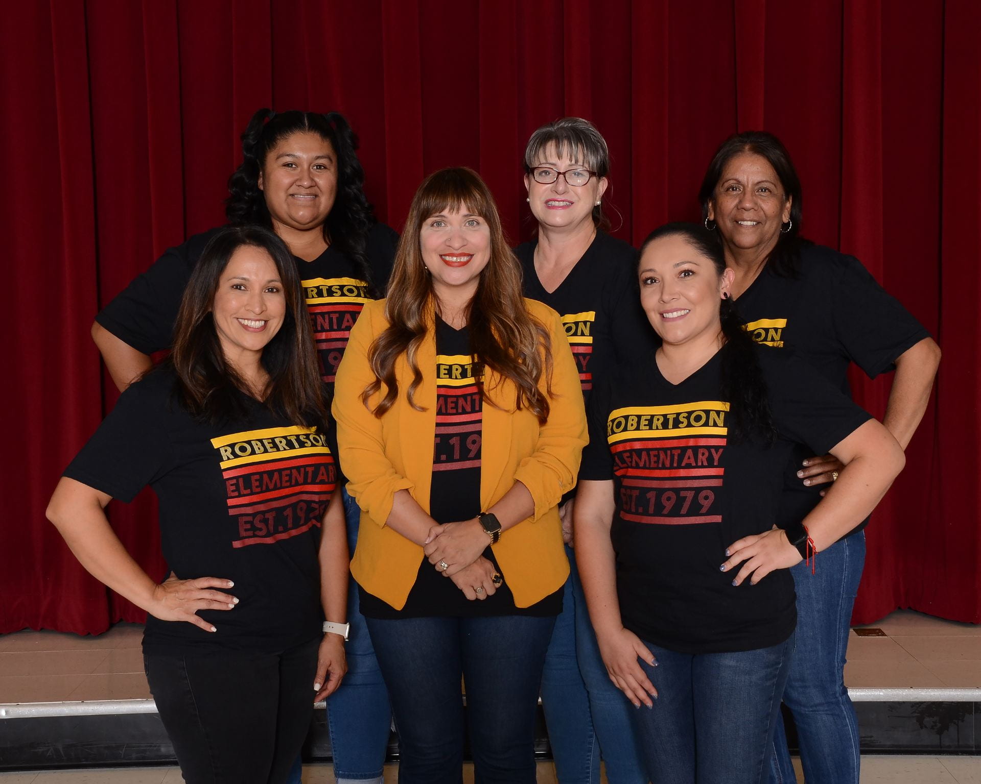 Front office and administrative staff members wearing matching school shirts, on a dark background.